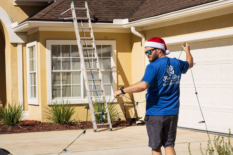 Crew member in a Santa hat laying out a strand of bulbs in a driveway