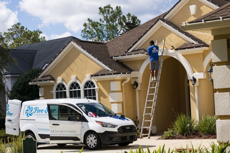 Five Star van parked at a home while a crew member installs lights from a ladder