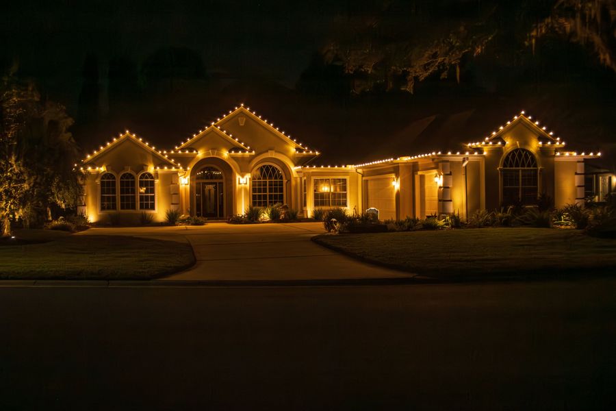 Single-story home with lights tracing every peak and the arched entry
