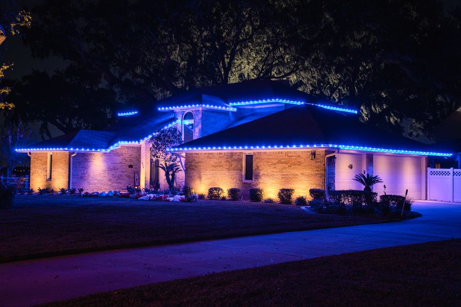 Home lit in blue along the roofline with warm uplighting